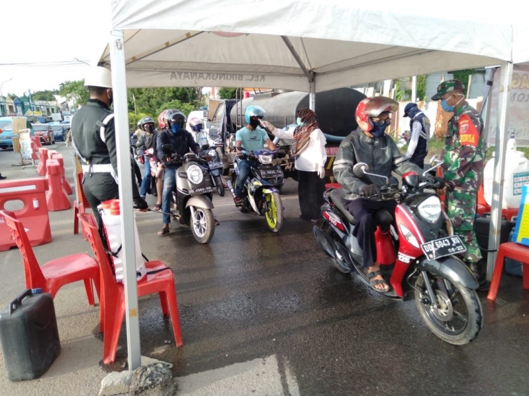 Pengendara melewati posko pemeriksaan cek poin di perbatasan Makassar - Maros, Minggu (03/05/2020).