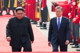 Presiden Korea Selatan Moon Jae-in dan pemimpin Korea Utara Kim Jong Un menghadiri upacara penyambutan di desa gencatan senjata Panmunjom di dalam zona demiliterisasi yang memisahkan kedua Korea, Korea Selatan, Jumat (27/4/2018). Foto : (Korea Summit Press Pool/Pool via Reuters)
