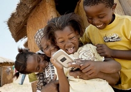 Sekumpulan Afrika menyaksikan layar yang ada dalam telepon genggam | sumber: telecomdrive.com