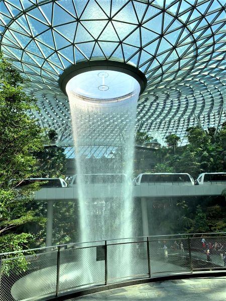 Skytrain melintas di atas dekat air terjun HSBC Rain Vortex, Bandara Changi Singapura. (Foto: Gapey Sandy)