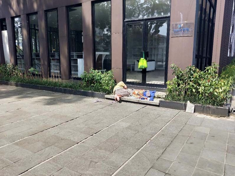 Seorang tuna wisma tidur siang di pintu masuk gedung perpustakaan. (foto: dok. pribadi)