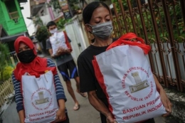 Warga membawa bingkisan berupa bantuan sosial dari Presiden di Cibeunying Kidul, Bandung, Jawa Barat, Senin (04/05). (ANTARA FOTO/RAISAN AL FARISI) dipublikasikan Kompas.com