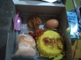 Nasi kuning, salah satu menu sarapan pagi di lokasi karantina, lengkap dengan satu kotak susu UHT. / Foto : Elvidayanty. 
