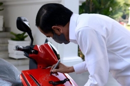Presiden Jokowi membubuhkan tandatangan pada motor listrik Gesits yang dimenangi M Nuh lewat lelang--grid.id