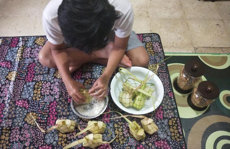 Mengisi cangkang ketupat dengan beras. (foto: dok. pribadi)