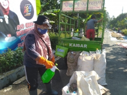 Roro Hendarti menyemprotkan cairan disinfektan ke kantong sampah/Foto: Lilian Kiki Triwulan