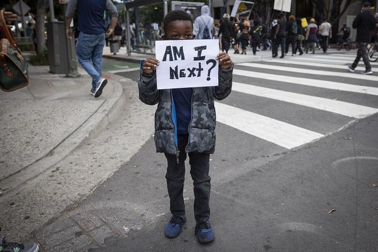 Seorang bocah lelaki kulit hitam memegang kertas bertuliskan Am I Next? saat protes di pusat kota Los Angeles, (AP/Christian Monter via kompas.com)
