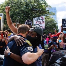 Seorang Demonstran kulit hitam memeluk polisi kulit putih. Sumber foto : Akun facebook Steve Stene Njenga