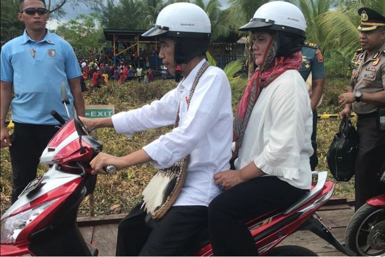 Presiden Jokowi memboncengi Ibu Iriana dengan sepeda motor listrik saat blusukan di Kota Agats (kompas.com)