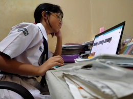 Seorang siswi Sekolah Menengah Pertama tengah serius mengerjakan UKK secara daring - Sumber Foto: Dokpri/IST