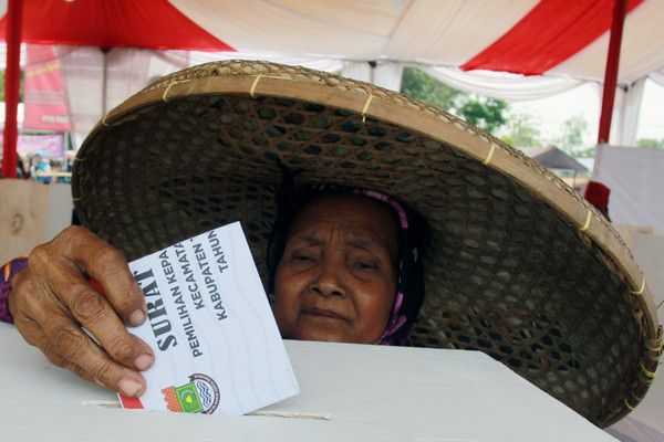 Seorang ibu  sedang memasukan surat suara  pada saat Pemilihan Kepala Desa (Sumber Gambar: jurnaljabar.id)