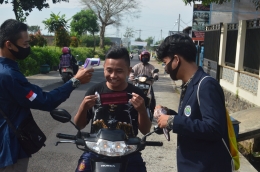 Mahasiswa KKN sedang membagikan masker pada pengendara sepeda yang akan memasuki Desa Langlang | dokpri