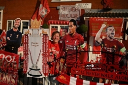 Emily Farley (tengah) berdiri di depan rumahnya untuk merayakan keberhasilan Liverpool menjadi juara Premier League, kasta teratas Liga Inggris, musim 2019-2020, Kamis (25 Juni 2020). (Foto: AFP/ OLI SCARFF via kompas.com)