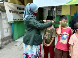 Thia Liani yang Sedang Membagikan Masker Kepada Anak-Anak