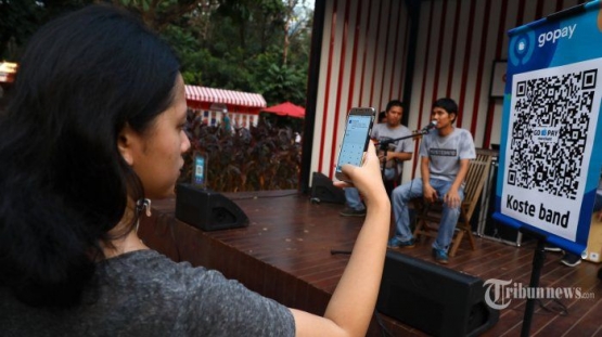 Seorang pengunjung GoFood Festival memberikan apresiasi kepada Koste Band, musisi jalanan binaan Institut Musik Jalanan (IMJ) menggunakan GoPay di area Gelora Bung Karno Jakarta [Sabtu, 17/8/2019]. (Foto: Tribunnews/Irwan Rismawan)