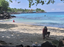 Seorang Pria membersihkan Pantai, wisatan yang mandi di bibir pantai dan menaiki karang . Dokpri