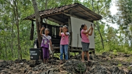 Tiga orang murid SD berusaha mencari sinyal dengan ponsel mereka di Gunung Kidul, Yogyakarta (voaindonesia)