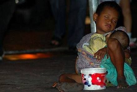 Seorang anak yang mengemis tertidur sambil menggendong adiknya (solopos.com)