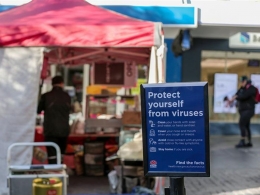 Poster ingatkan untuk lindungi diri dari virus corona di gerai makanan di  Sydney, Australia, 19/6-2020. (Foto: xinhuanet.com/Xinhua/Bai Xuefei)