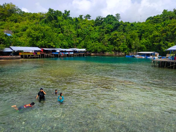 Seorang ibu mengajari anak-anaknya berenang di pantai wisata Jikomalamo | Foto: Dokumentasi Pribadi