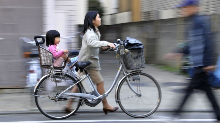 Ibu mengendarai sepeda dengan putrinya (media.pri.org)