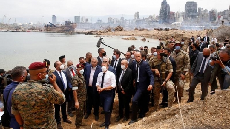 PM Prancis Emmanuel Macron tiba di Beirut, 06/ 08/ 2020. Tampak latar belakang foto puing-puing sisa ledakan 2.750 ton amonium nitrat yang menewaskan 150 orang lebih (Foto: Thibault Camus/ Reuters)