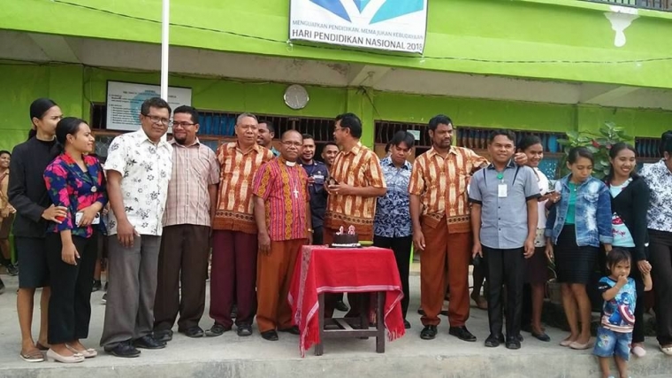 Saya (berdiri ke-3 dari kiri depan) berfoto bersama sesama para staf guru SMA Kristen Atambua pada tahun 2019 di depan ruang guru-guru. (Foto: Dokpri).