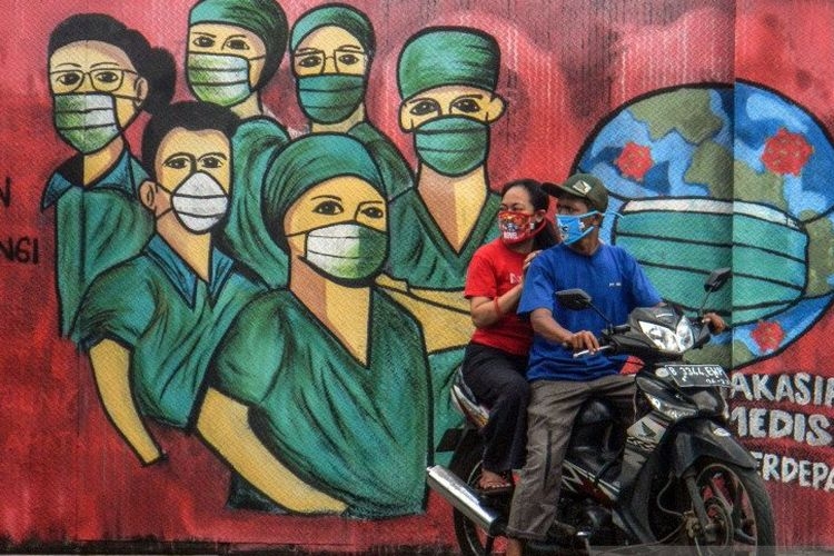 Pengendara motor melintas di depan mural tentang pandemi virus corona atau COVID-19 di Jalan Raya Jakarta-Bogor, Depok, Jawa Barat, Jumat (3/4/2020). | Sumber: ANTARA FOTO/Yulius Satria Wijaya/pras