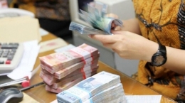 Ilustrasi seorang karyawan menghitung mata uang dalam bentuk pecahan Rp 50.000 dan pecahan Rp 100.000. Hari ini, pemerintah akan membagikan gaji ke-13 untuk pegawai negeri sipil (PNS) TNI Polri. | Foto: kaltim.tribunnews.com