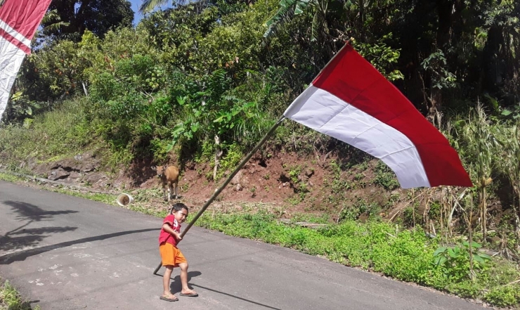 seorang anak sedang berusaha mengangkat tiang bendera merah putih. foto: whatsapp/kim