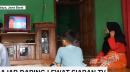 Seorang anak didampingi orangtuanya saat melakukan pembelajaran jarak jauh lewat siaran TV sekolahnya | Sumber: CNN Indonesia