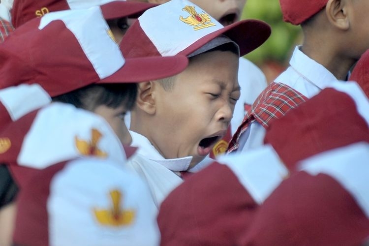 Salah satu siswa menguap di sela upacara bendera pada hari pertama masuk sekolah di Sekolah Dasar Negeri (SDN) 243 Palembang, Sumatera Selatan, Senin (16/7). (ANTARA FOTO/Feny Selly)