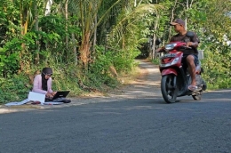 Seorang mahasiswi di Magelang harus rela mengerjakan ujian di pinggir jalan demi dapat sinyal (Sumber Foto: tribunnews.com)
