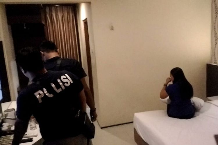 Dua penyidik reskrim Polres Madiun Kota menggeledah kamar hotel yang digunakan tempat prostitusi online, Selasa (14/1/2019). (Foto: KOMPAS.com/MUHLIS AL ALAWI)