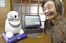 Setsuko-san dan robot PaPeRo-i yang menyapanya (sumber: straitstimes.com)