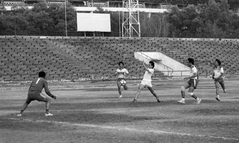 LIEM SWIE KING -- Ujung tombak kesebelasan Pelatnas Bulu Tangkis Indonesia, Liem Swie King (putih-putih) bersiap menembakkan bola ke gawang JB Suratno (Kompas), di Stadion Madya tahun 1980-an. Di belakang, ada Yesayas Octovianus dan Oemar Samsoeri dari Kompas. Kompas dicukur gundul, nyaris mendekati 10 tanpa balas. (Foto: Dokumentasi Kompas)