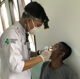 Foto : Dokter Aky sedang melakukan proses pemeriksaan dan pencabutan gigi pasien dari desa Patlean Jaya (dokpri).