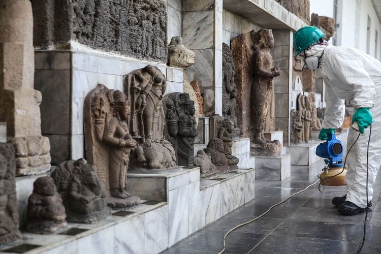 Petugas menyemprotkan cairan disinfektan disekitar patung-patung di halaman gedung A, Museum Nasional, Jakarta Pusat, Senin (16/3/2020). (Foto: KOMPAS.com/GARRY LOTULUNG)