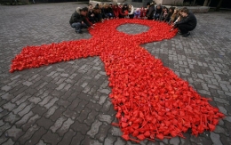 Aktivis membentuk pita merah sebagai simbol kampanye dunia melawan AIDS di Rusia, 2010 (Sumber: theconversation.com/Vladimir Konstantinov/Reuters).