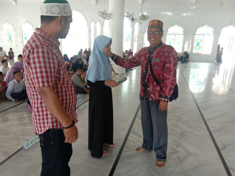 Ketua 1  PHBI Masjid Baitul Istiqamah Teupin Raya saat menyerahkan santunan kepada anak yatim
