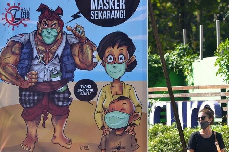 Ilustrasi: wisatawan wancanegara berjalan di dekat baliho sosialisasi penggunaan masker di kawasan Legian, Badung. (NTARA FOTO/FIKRI YUSUF via kompas.com)