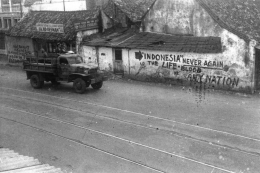 Truk tentara sekutu melintasi dinding-dinding bertuliskan semboyan perjuangan Indonesia, diduga kawasan Senen, Jakarta Pusat. (IPPHOS) (kompas.com)