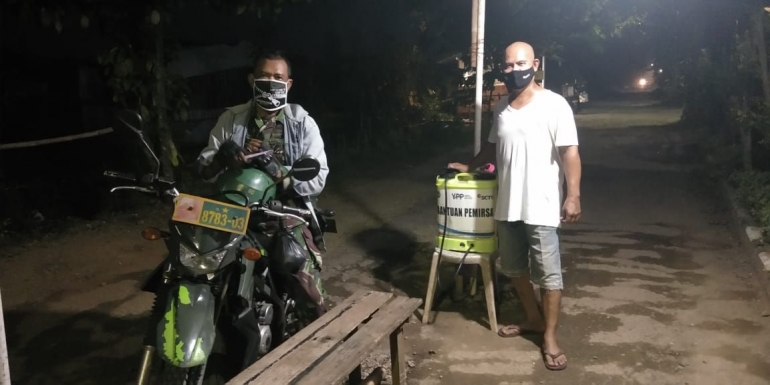 Bapak Agustusin Roba'I (Ketua RW desa Kalisuren) bersama salah satu anggota TNI di pos kesehatan untuk pengecekan suhu dan penyemprotan disinfektan. (Dokpri)