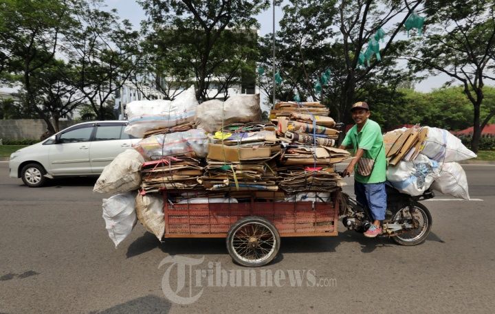 Seorang pemulung dengan sepeda motor yang sudah dimodifikasi menjadi gerobak melintas di Jalan Boulevard BSD Timur, Tangerang Selatan pada Jumat (22/6/2018)| Sumber: Warta Kota/Alex Suban via Tribunnews.com