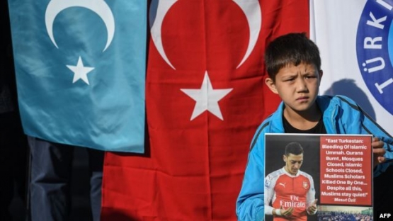 Seorang pendukung minoritas Muslim Uighur di Cina menunjukkan poster Mesut Ozil. | (Foto: AFP) via Voaindonesia.com