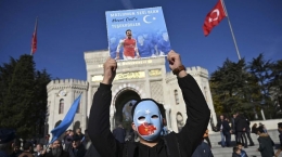 Seorang pendukung muslim Uighur di Cina memegang poster dukungan untuk Mesut Ozil bertuliskan, "Terima kasih karena sudah menjadi suara kami". | (Ozan KOSE / AFP) via CNN