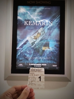 Sobekan tiket bioskop di depan poster film 