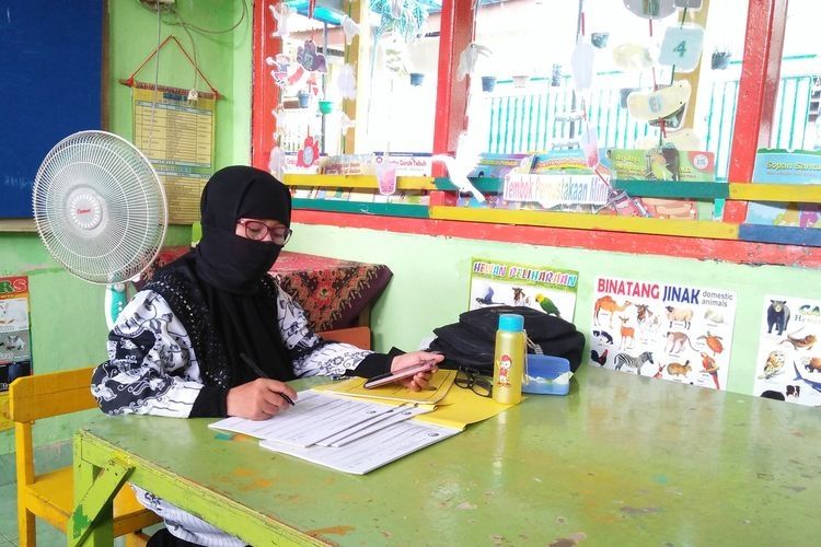 Siti Huroirohmatin, seorang guru honorer yang sedang mengoreksi tugas siswanya yang masih melaksanakan pembelajaran daring, Rabu (25/11/2020). (KOMPAS.COM/HAMZAH ARFAH)