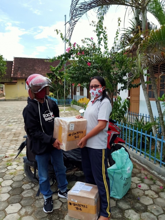 Ibu Reni Romawati menerima paket dari petugas JNE (foto: dokpri)