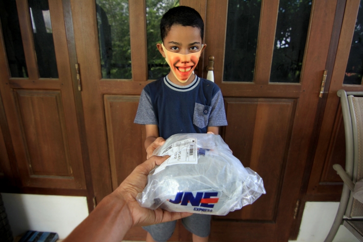 Senyuman lebar Amar saat menerima paket dari JNE